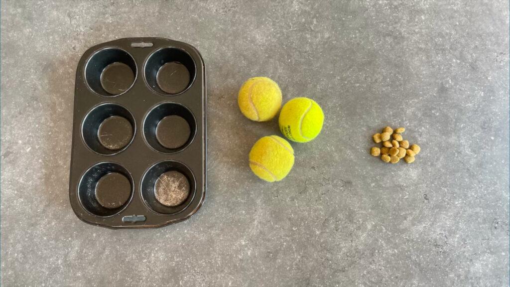 Benodigdheden; muffinblik, tennisballen, brokjes of snoepjes